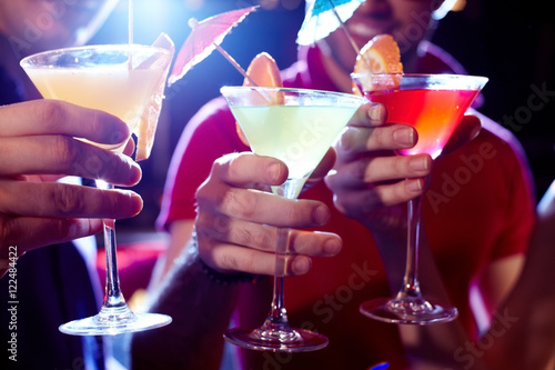 Close-up of three martini glasses in hands of young people