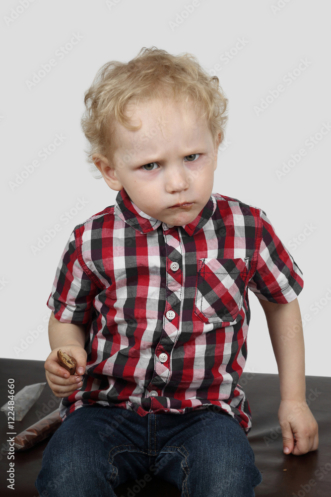 Little boy reluctantly offers candy on gray background - generosity and greed concept Little boy reluctantly offers candy on gray background - generosity and greed concept
