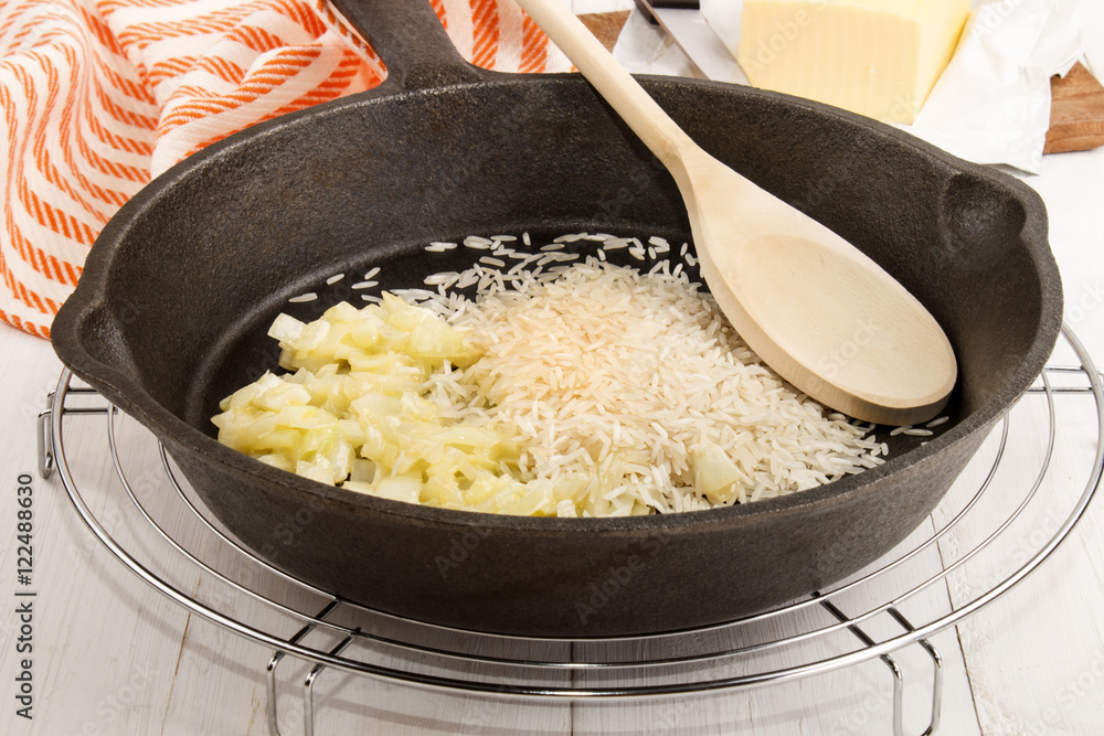 long grain rice and is sweated, glazed onions in a cast iron pan long grain rice and is sweated, glazed onions in a cast iron pan