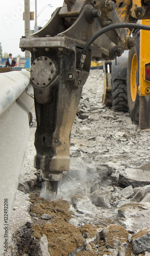 Excavator breaking and drilling the concrete road for repairing