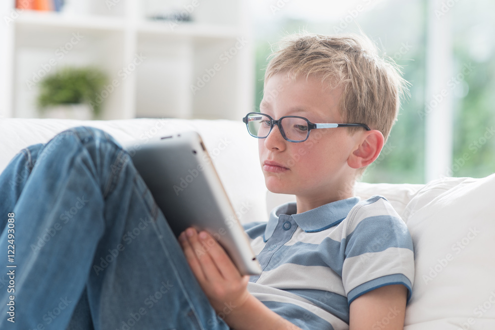At home, 8 years old boy having fun by surfing on a tablet At home, 8 years old boy having fun by surfing on a tablet
