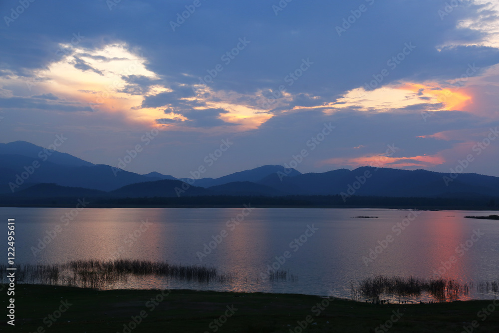 Fototapeta premium Rays of sun shining through the clouds and sunset over water