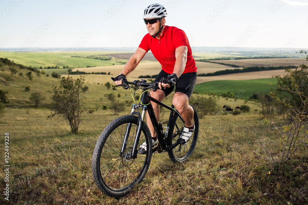 Young cyclist cycling in the spring meadow