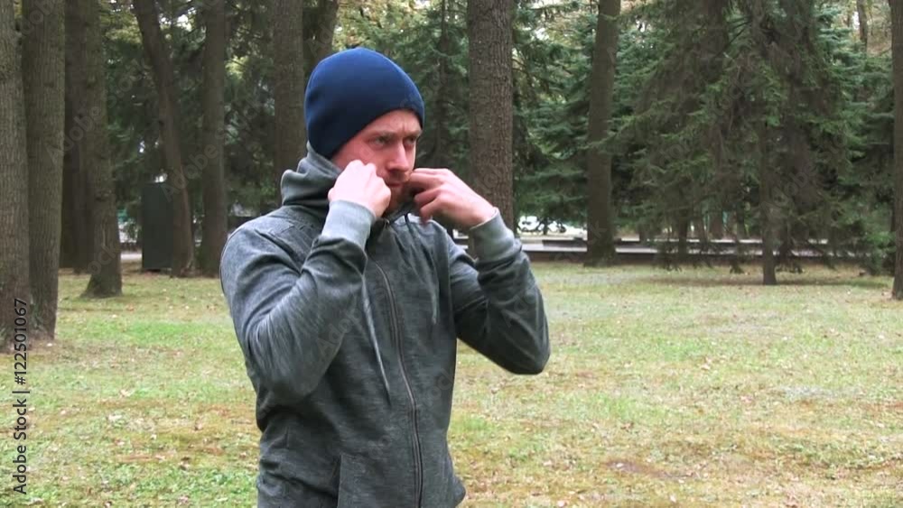 Bearded Young Man Is Preparing For Street Workout In The Park Zipping Up His Grey Hoodie Bearded Young Man Is Preparing For Street Workout In The Park Zipping Up His Grey Hoodie