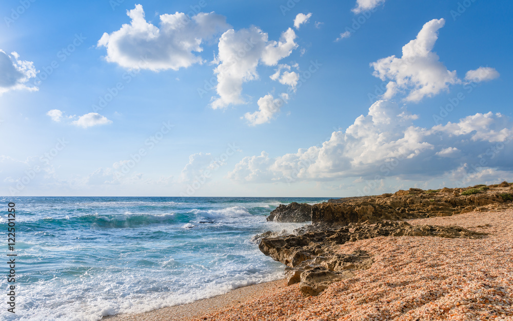 Mediterranean sea with waves and shell beach at sunny summer day. 