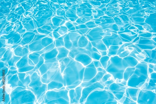 Blue water surface with sun reflection in swimming pool