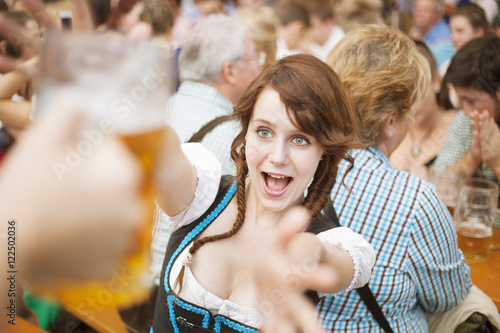 Excited girl reaches for a mug of beer at Oktoberfest 
