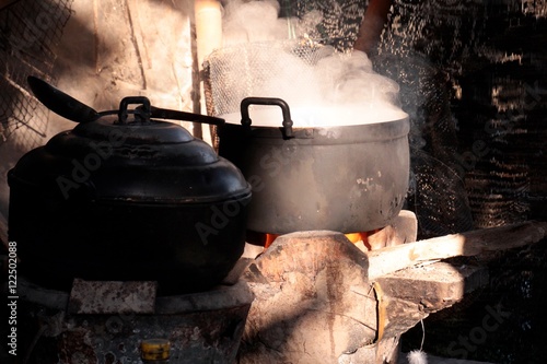 Old pot of food cooking on burning wood fire stove