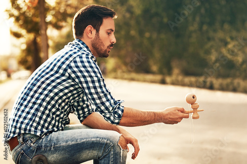 Young man enjoying outside and playing by kendama.