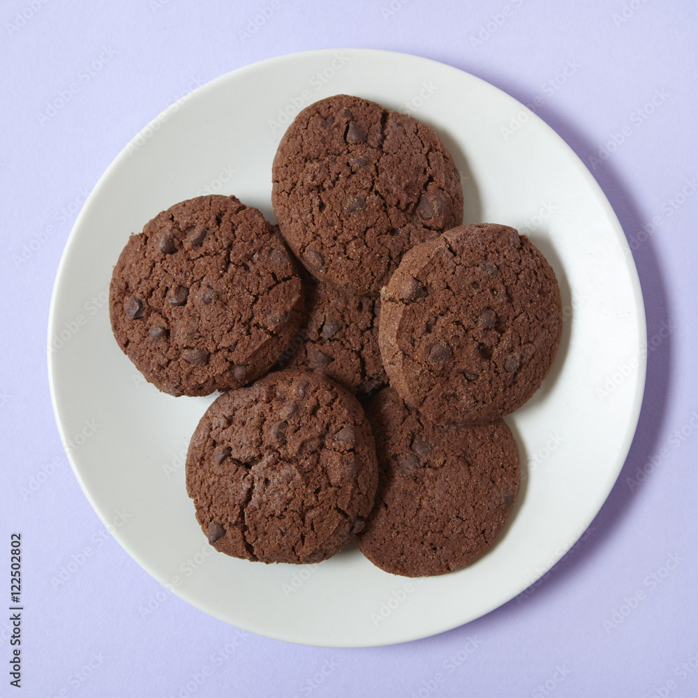A plate of chocolate chunk cookies on a pale purple background A plate of chocolate chunk cookies on a pale purple background