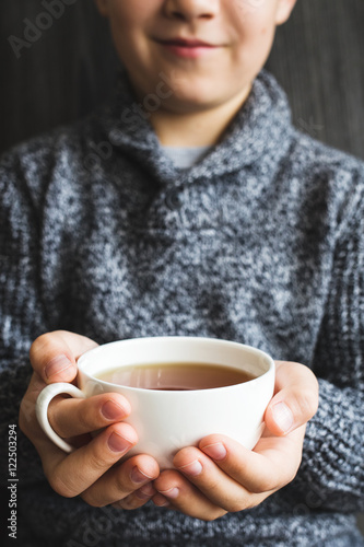 Youngster holding a white cup in his hands