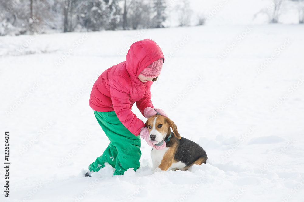 Little girl playing with her dog in a snowy landscape