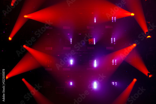 Stage lights of different colors, background of glowing red spotlights