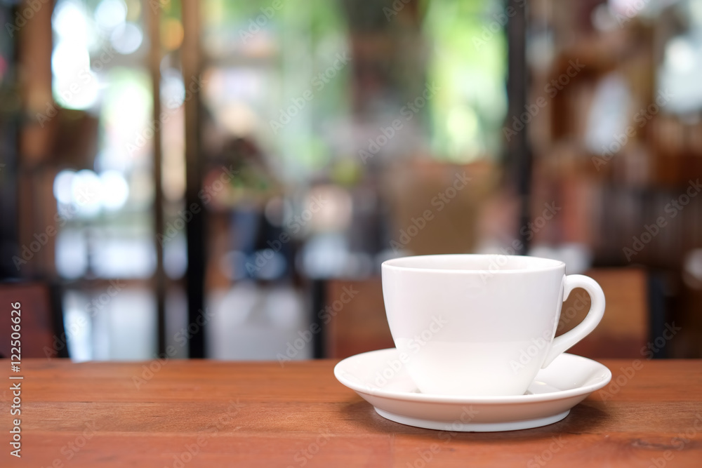 White coffee cup on wooden table with blurred cafe background.