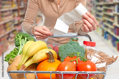 Woman with grocery receipt and shopping cart.