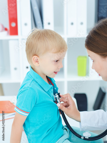 Female doctor examining a child patient by stethoscope. 