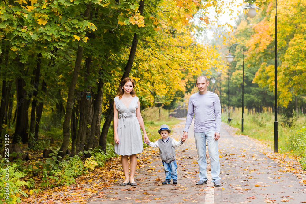 Fototapeta premium Young family walking in the park an autumn day