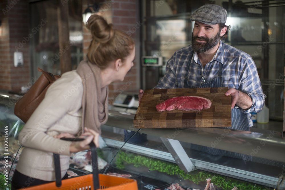 Butcher showing meat to woman in butchery Butcher showing meat to woman in butchery