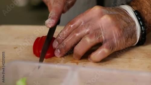 cooking and outdoor concept - close up of male hand cutting tomato on cutting board with sharp knife photo