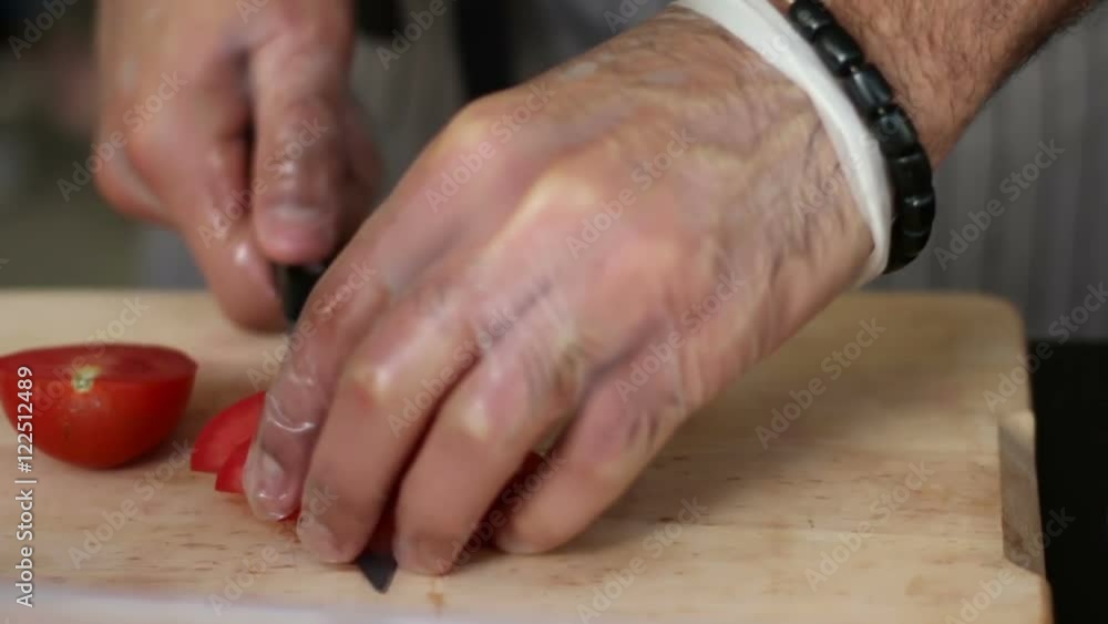 cooking and outdoor concept - close up of male hand cutting tomato on cutting board with sharp knife cooking and outdoor concept - close up of male hand cutting tomato on cutting board with sharp knife
