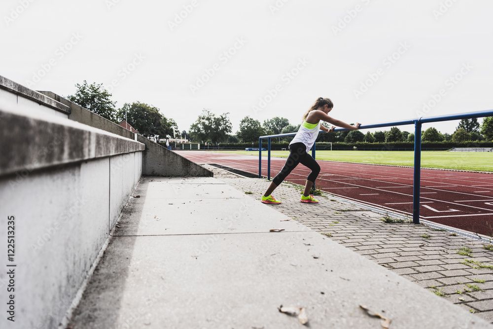 Young woman stretching in a track and field stadium Young woman stretching in a track and field stadium