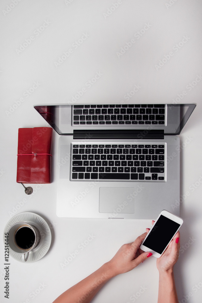 Woman holds smart phone. Top view white desk with computer, vint Woman holds smart phone. Top view white desk with computer, vint