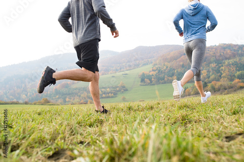 Legs of unrecognizable couple running in autumn nature