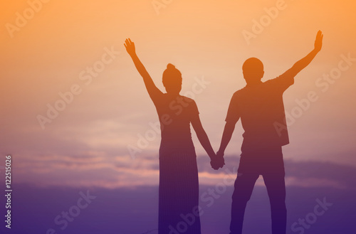 Young couple hand up at sunset on the Mountain