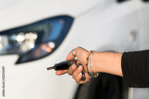 Woman using electronic key to close the car and switch on the alarm system.