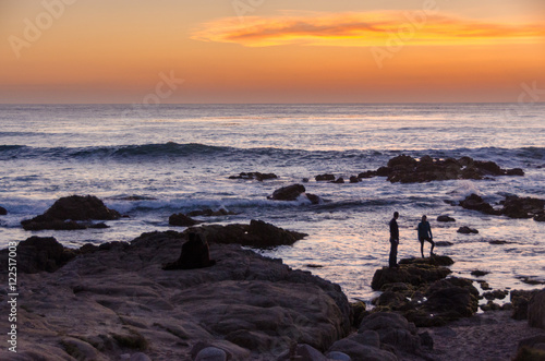 Ocean sunset with people standing on rocks