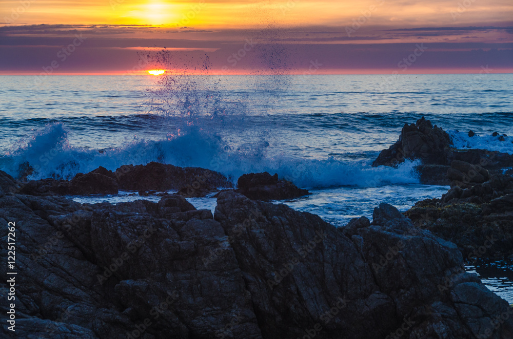 waves crashing against rocks at sunset over the sea waves crashing against rocks at sunset over the sea