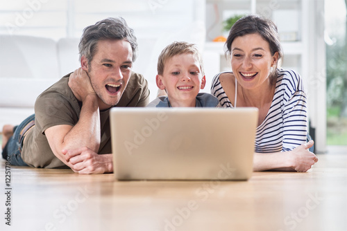 At home, cheerful family sharing a funny video on a laptop © jackfrog
