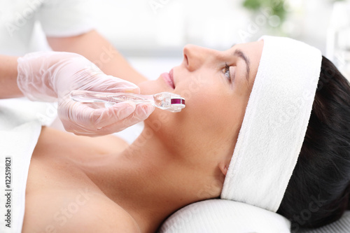 Kobieta w salonie kosmetycznym na zabiegu mezotrrapii mikroig  owej z u  yciem rollera.