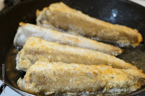 Fried hake fish fillet in a frying pan