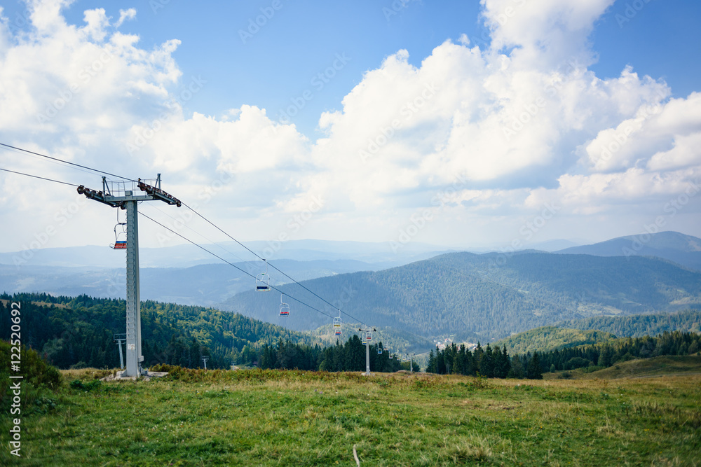 Top of the hill with lift in Carpathian mountains. Beautiful blue sky with clouds in the background. Summer time. Top of the hill with lift in Carpathian mountains. Beautiful blue sky with clouds in the background. Summer time.