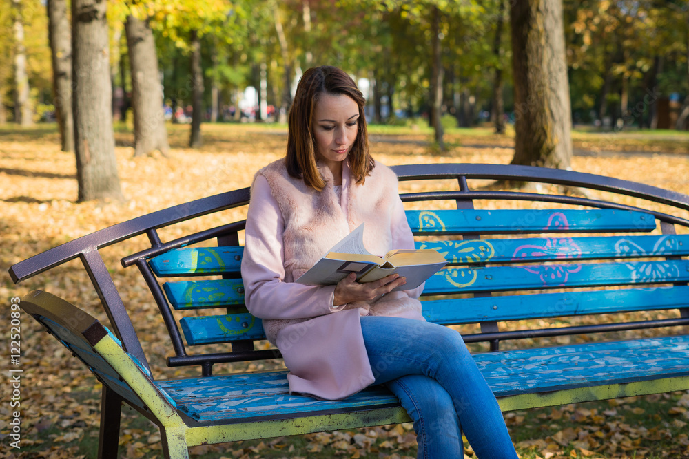 Obraz premium Girl reading a book in autumn park