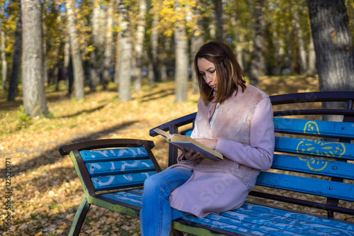 Girl sits on a park bench and reading a book