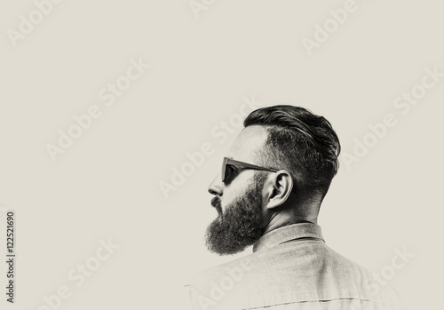 Black and white portrait of a Bearded Man in a denim shirt and glasses  on toned background. There is a spase for your text.