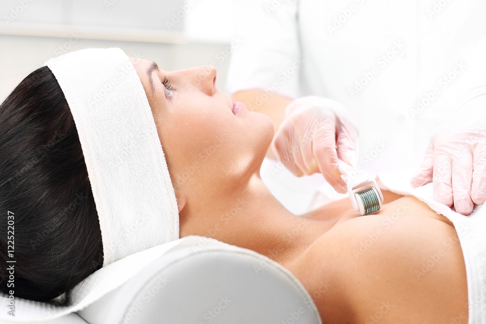 Mezoterapia, kosmetyczka nakłuwa dekolt kobiety rolka do mezoterapii igłowej.
