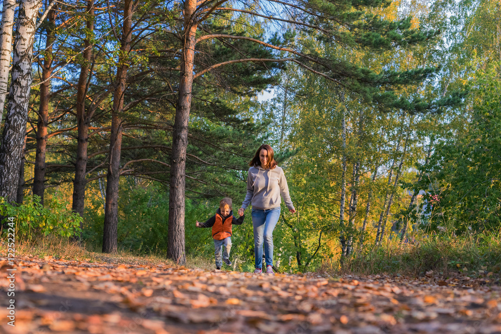 Mother and son running on path in autumn forest Mother and son running on path in autumn forest