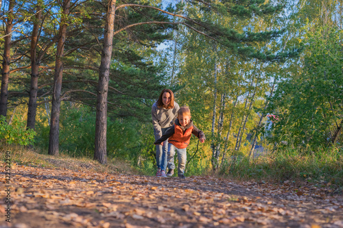 Mother and son running on path in autumn forest