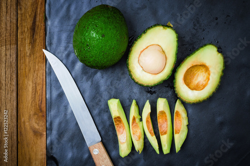 Avocado fruit and sliced avocad on black photo