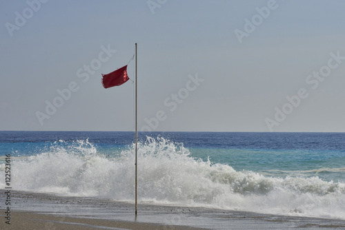 Bandiera rossa in spiaggia con mare agitato
