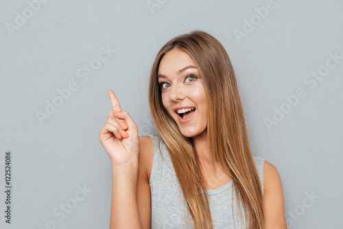 Young happy woman poiting finger up at copyspace
