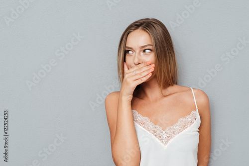 Young girl covering her mouth and looking away isolated