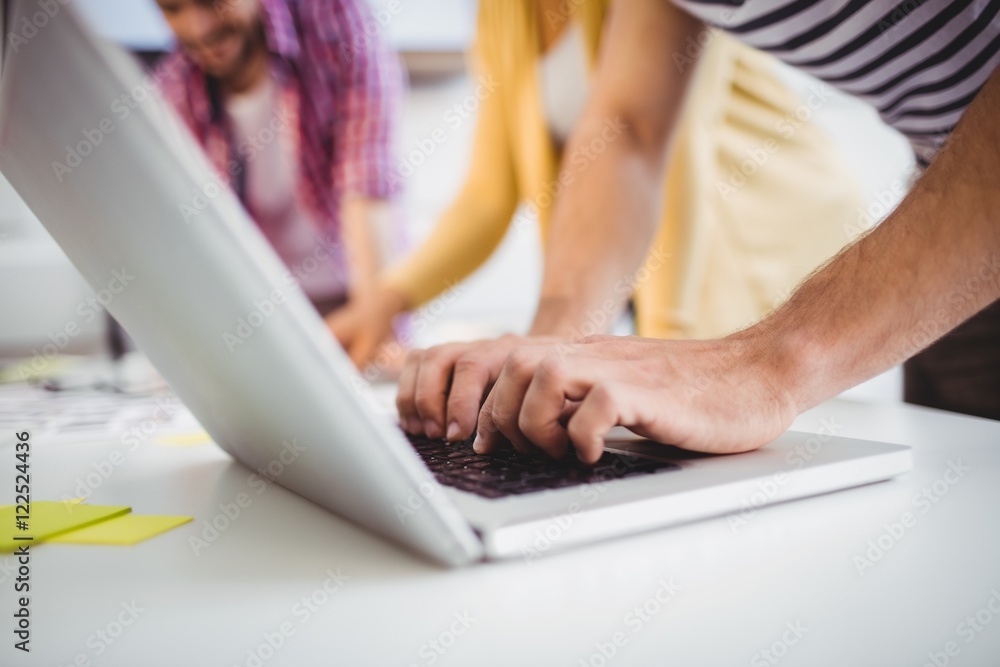 Fototapeta premium Close-up of executive typing on laptop at creative office