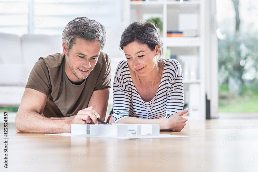 At home, young couple study a model house of a building project At home, young couple study a model house of a building project