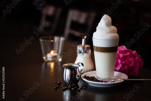 Front-view of latte machiato decorated with coffee beans, sugar