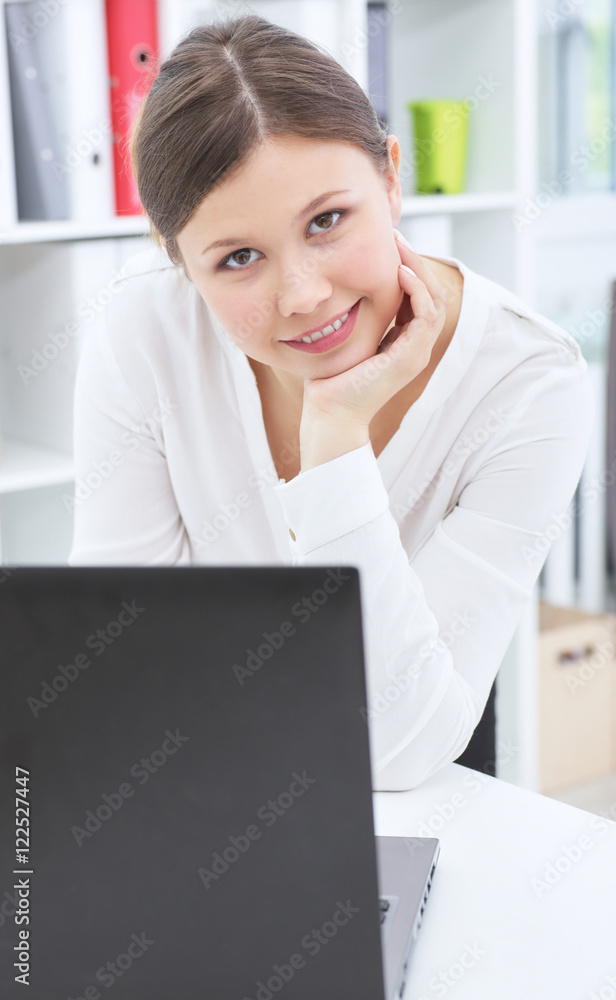 Portrait of a young smiling secretary working with laptop in her office. Portrait of a young smiling secretary working with laptop in her office.