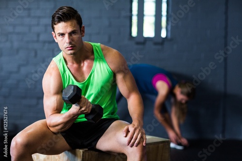 Portrait of serious man lifting dumbbell in gym